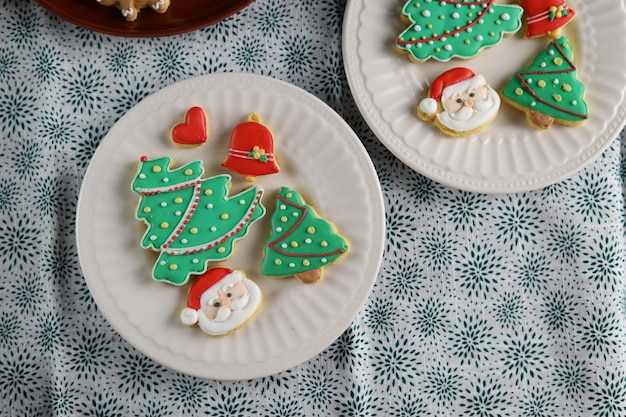 Weihnachtsplätzchen mit Weihnachtsbaumform serviert in weißer Platte mit weißem Hintergrund.