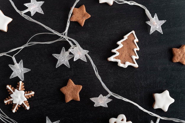 Weihnachtsplätzchen Sterne Tanne und Girlande auf schwarzem Hintergrund Lebkuchen