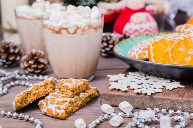 Weihnachtsplätzchen und heißer Kakao mit Eibischen in den Gläsern auf dem Tisch mit Weihnachtsdekorationen