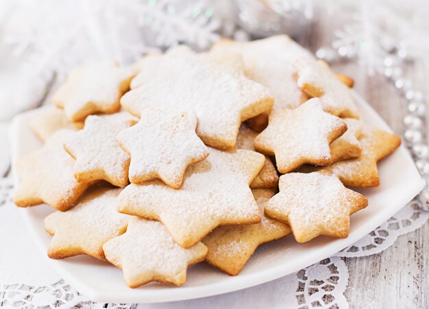 Weihnachtsplätzchen und -lametta auf einem Holztisch