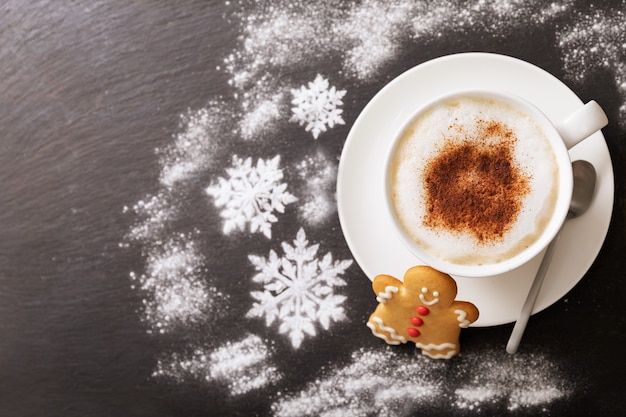 Weihnachtsplätzchen und Tasse Cappuccino auf dunklem Hintergrund, Ansicht von oben