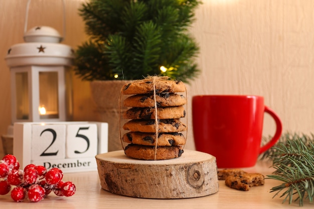 Weihnachtspostkarte mit Schokoladenplätzchen auf Holzständer rote Tasse Weihnachtsbaum latern und Kalender