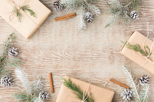 Weihnachtsrahmen aus verschneiten Tannenzweigen, Tannenzapfen, Geschenkbox aus braunem Kraftpapier. Weihnachtstapete. Flache Lage, Ansicht von oben, Kopienraum