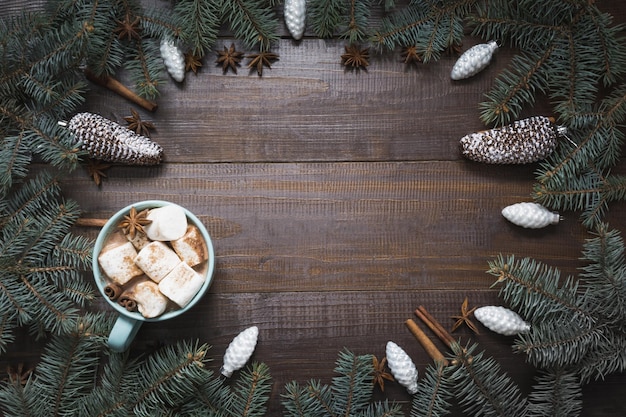 Weihnachtsrahmen mit weißen Verzierungen, Kegelspielzeug, Kugeln, Zimt auf Holzbrett, Weihnachtskarte