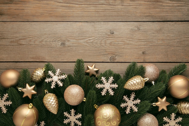 Weihnachtsrahmen - Äste mit Goldkugeln, Sternen, Schneeflocken auf grauem Hintergrund. Ansicht von oben