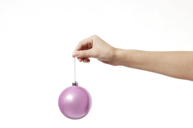Weihnachtsrosa Spielzeugball für den Weihnachtsbaum in der Hand lokalisiert auf einem weißen Hintergrund.