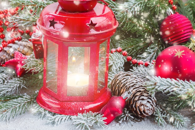 Weihnachtsrot leuchtende Laterne hautnah mit Tannenbaum und fallendem Schnee