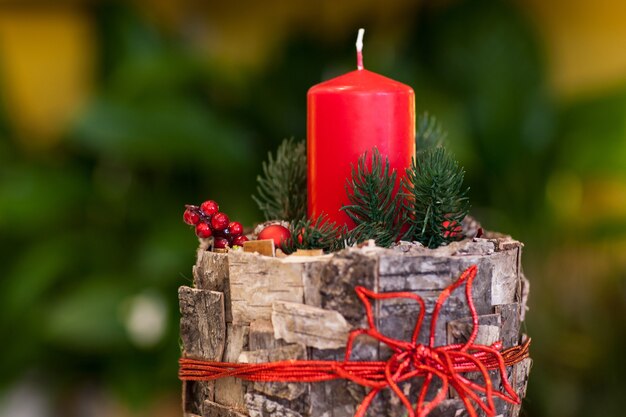 Foto weihnachtsrote kerze auf einem baumstumpf verzierte baumrinde und beeren und tannenzweige