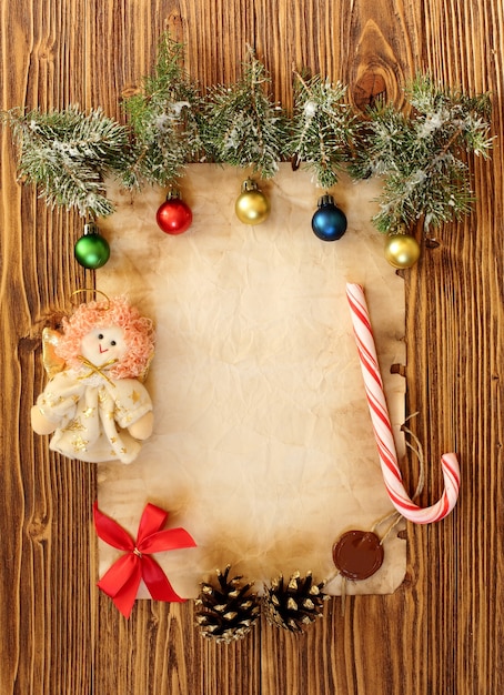 Weihnachtsschmuck auf dem alten Blatt Papier auf Holzuntergrund, Platz für Text