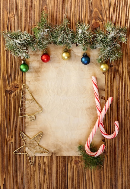 Weihnachtsschmuck auf dem alten Blatt Papier auf Holzuntergrund, Platz für Text
