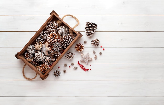 Weihnachtsschmuck Hintergrund Tannenzapfen in Holzkiste auf weißem Holztisch