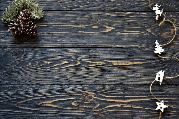 Weihnachtsschmuck, Kegel und Tannenzweig auf einem dunklen hölzernen Hintergrund. Draufsicht. Festlicher Hintergrund.