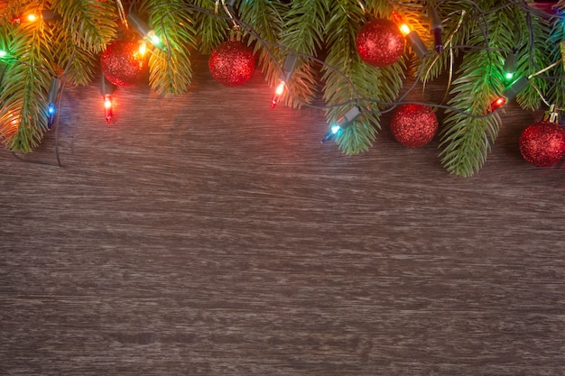 Weihnachtsschmuck mit Zweigen von Tannenbaum Weihnachtsbeleuchtung Ball und Tannenzapfen auf Holz