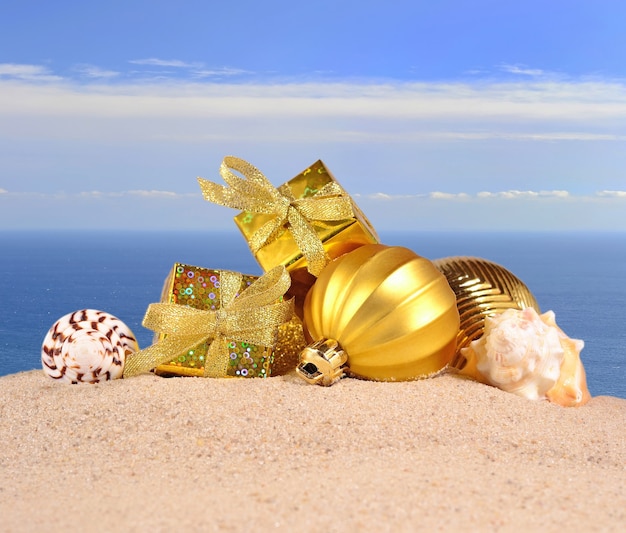 Weihnachtsschmuck und Muscheln auf einem Strandsand vor dem Hintergrund des Meeres