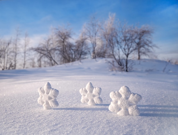 Weihnachtsschneeflocken auf weißem Schnee auf dem Hintergrund der Bäume. Winter frostigen sonnigen Tag.