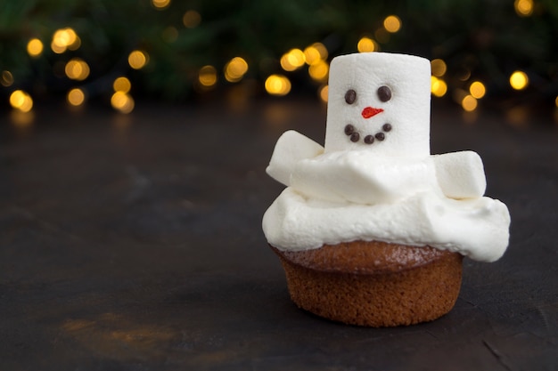 Weihnachtsschokoladenkleine kuchen mit Schneemanndekor. auf dunklem Hintergrund.