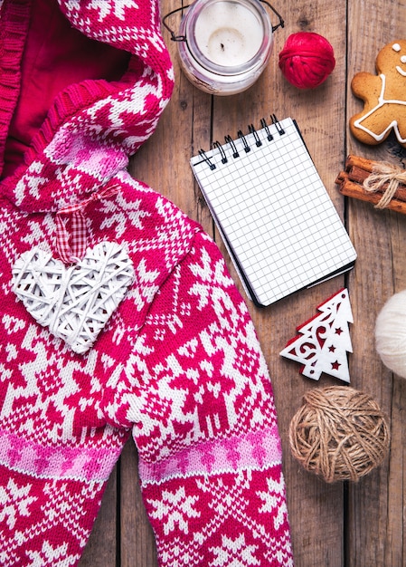 Weihnachtsset. Warme Decke, Pullover, Cle, Notizbuch, Gewürze, Zimt, Tannenzapfen, Herz auf dem Holz