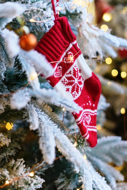 Weihnachtssocke gestrickte Verzierung auf weißem Schneebaum. Vertikaler unscharfer Hintergrund.