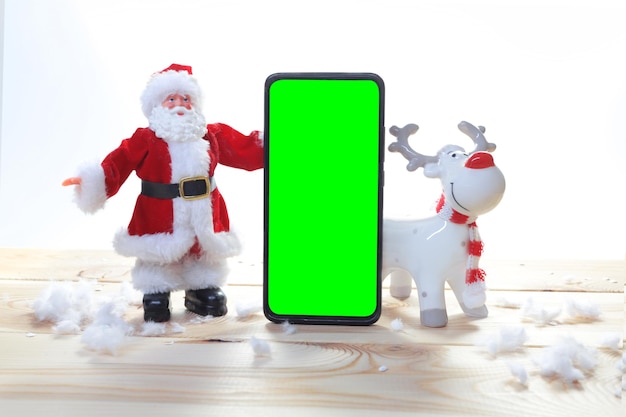 Foto weihnachtssockel mit telefon-chromakey-stillleben mit einer weihnachtskarte mit weihnachtsmann und einem tiefen