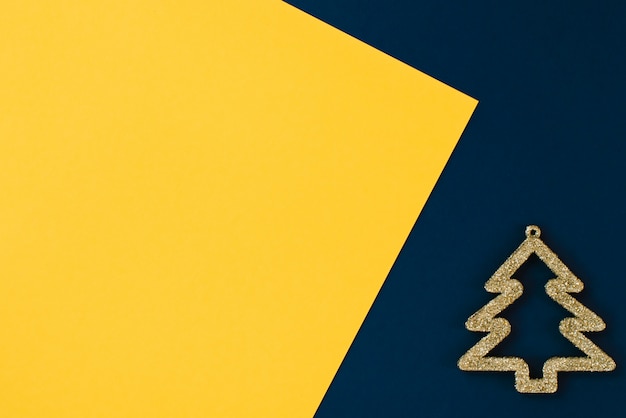 Weihnachtsspielzeug stilisierte Goldweihnachtsbaum auf einem bunten Gelb und einem Blau