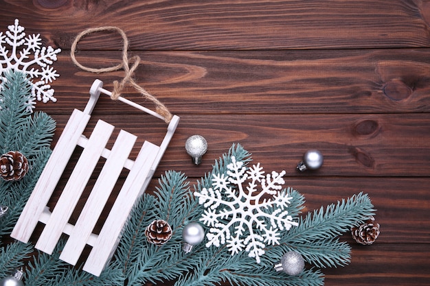 Weihnachtsspielzeugschlitten mit Tannenbaumast auf einem braunen Hintergrund.