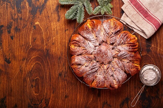 Weihnachtsstern geflochtenes Schokoladen- und Zimtbrot auf altem Muskelholztisch. Kopieren Sie Platz für Text. Ansicht von oben