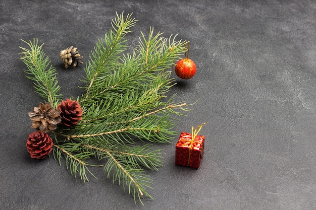 Weihnachtsstillleben von Tannenzapfen, Tannenzweigen und rotem Spielzeug. Schwarzer Hintergrund. Speicherplatz kopieren. Draufsicht