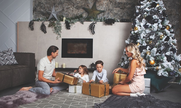 Weihnachtsstimmung Familie von Mama Papa Tochter Sohn offene Geschenke Geschmückter Weihnachtsbaum und Kamin