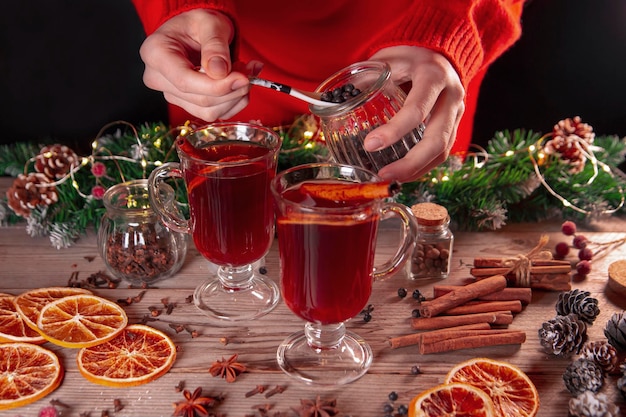 Foto weihnachtsstimmung urlaubsatmosphäre das mädchen bereitet glühwein auf einem holztisch zu