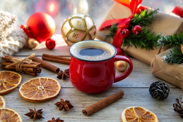 Weihnachtsstimmung Urlaubsatmosphäre Rote Tasse Kaffee Weihnachtsgeschenkboxen Weihnachtsbaum goldene Kugel Kegel Sternanis Zimt auf einer hölzernen Fensterbank