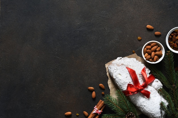 Weihnachtsstollen mit rotem Band als Geschenk auf einem Betontisch.