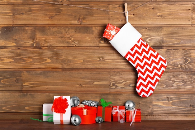 Weihnachtsstrumpf und Geschenke gegen Holzwand