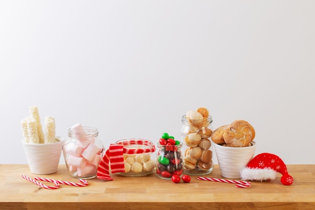 Weihnachtssüßigkeiten und -plätzchen in Gläsern auf Holzregal auf weißem Hintergrund