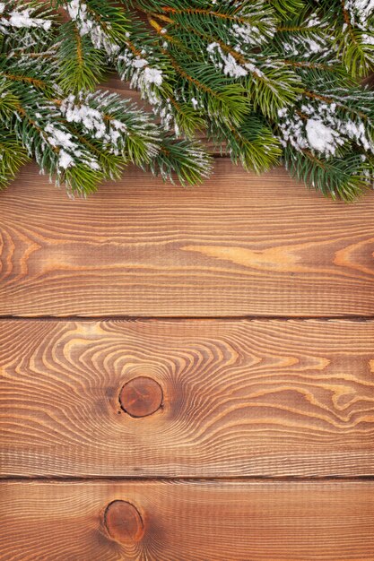 Weihnachtstanne mit Schnee auf rustikalem Holzbrett