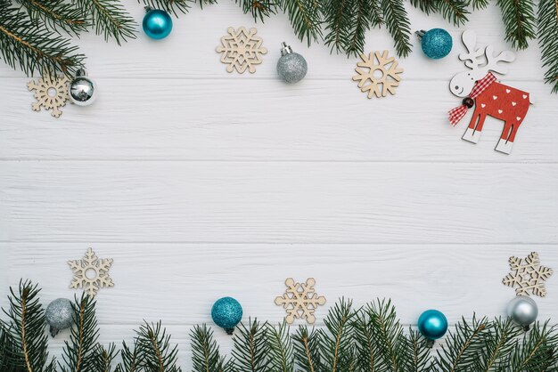 Weihnachtstannenbaum mit Dekoration und Glitzern auf hölzernem Hintergrund. Weihnachtshintergrund auf dem weißen hölzernen Schreibtisch