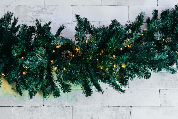 Weihnachtstannenbaum mit Lichtern auf weißem Backsteinhintergrund mit Kopienraum