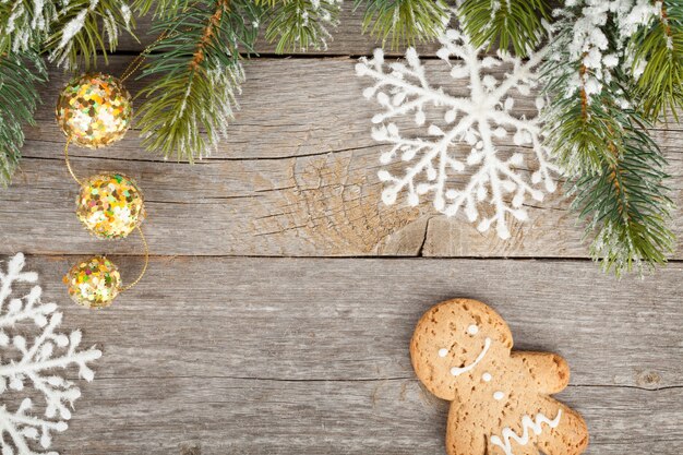 Weihnachtstannenbaum und -dekor bedeckt mit Schnee auf Holzbretthintergrund