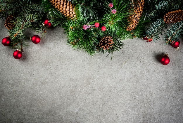 Weihnachtstannenbaumast mit Kiefernkegeln und Dekorationen auf grauer Steintabelle. Draufsicht, Exemplar