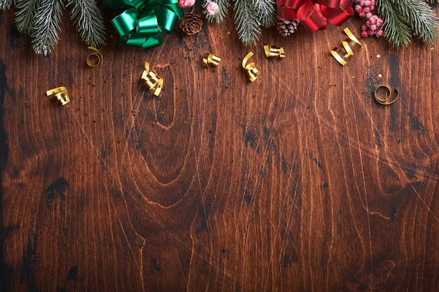 Weihnachtstannenzweige, Weihnachtskugeln, Geschenkbox, Holzschneeflocken und Sterne auf altem Holzhintergrund für Ihre Weihnachtsgrüße. Draufsicht mit Kopienraum. Weihnachtsgrußkarte.