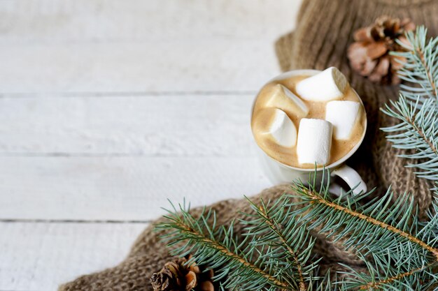 Weihnachtstasse kaffee, Schal und grüne Tannenzweige auf weißem hölzernem Hintergrund, Kopienraum