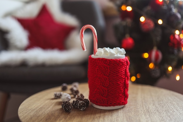 Weihnachtstasse Kakao mit Marshmallows, auf einem Holztisch vor dem Hintergrund eines Weihnachtsbaums. Neujahrsstimmung.