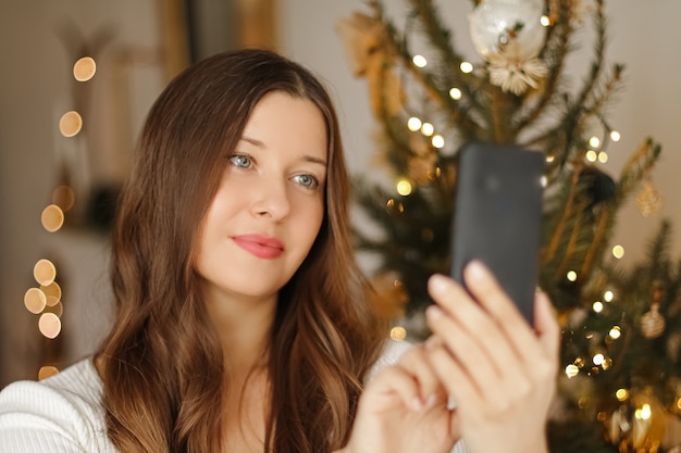 Weihnachtstelefonanruf und Urlaubsgrußkonzept glücklich lächelnde Frau mit Handy auf Weihnachten...