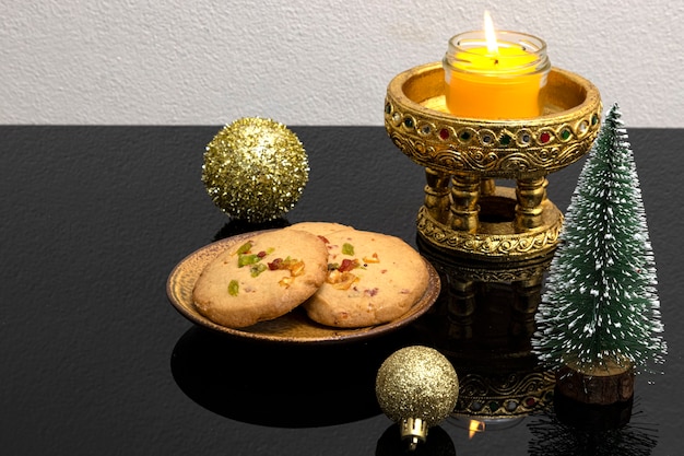 Weihnachtstischdekoration mit Duftkerze und einem Teller Orangenschalenkekse
