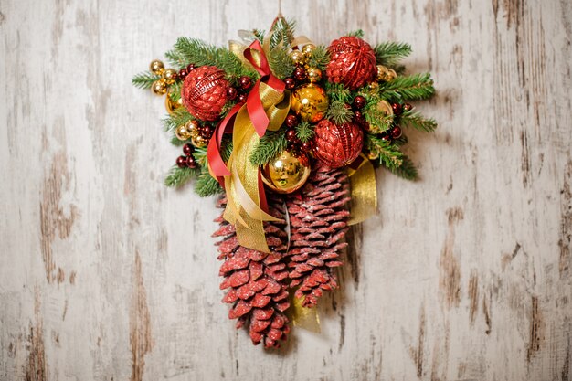 Weihnachtstürdekoration aus Tannenbaum, roten und goldenen Glaskugeln und farbigen Zapfen