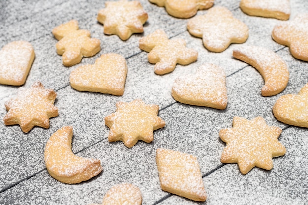 Weihnachtsverschiedene geformte Plätzchen mit Zuckerpulver auf Holztisch