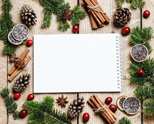 Weihnachtsverzierungen mit Tannenbaum und leerem Notizbuch auf hölzerner rustikaler Tabelle