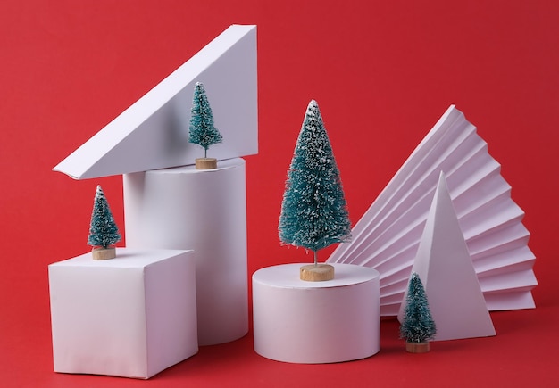 Weihnachtsvitrine Geometrische Formen Mini-Weihnachtsbäume auf rotem Hintergrund Konzeptkunst-Minimalismus