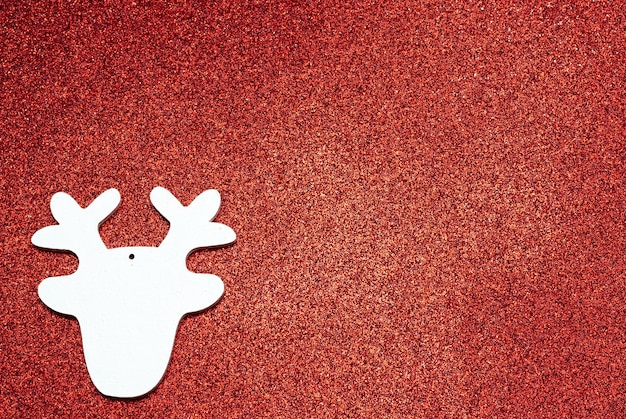 Weihnachtsweißes handgemachtes Holzspielzeug in Form eines Hirschkopfes auf einem glitzernden Hintergrund
