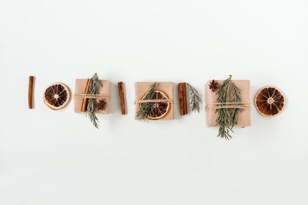 Weihnachtswohnung lag Zusammensetzung der handwerklichen Geschenkboxen auf der handgemachten braunen Papierbox mit Weihnachtsbaumzweig und Zimtstangen und trockener Orange.