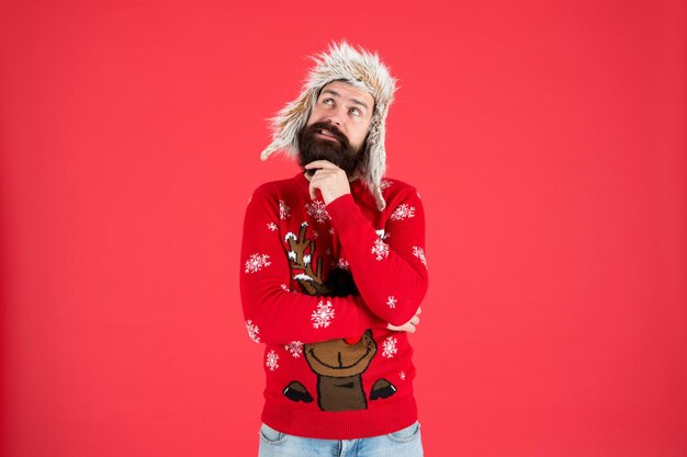 Weihnachtswunsch machen. Lebensverändernde Entscheidung. Hipster bärtiger Mann trägt Winterpullover und Hut. Frohes neues Jahr. Winterparty-Outfit. Mann nachdenklicher Gesichtsausdruck. Schwere Entscheidung. Entscheidung fällen.